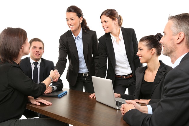 A group of six professionals in business attire are seated at a conference table