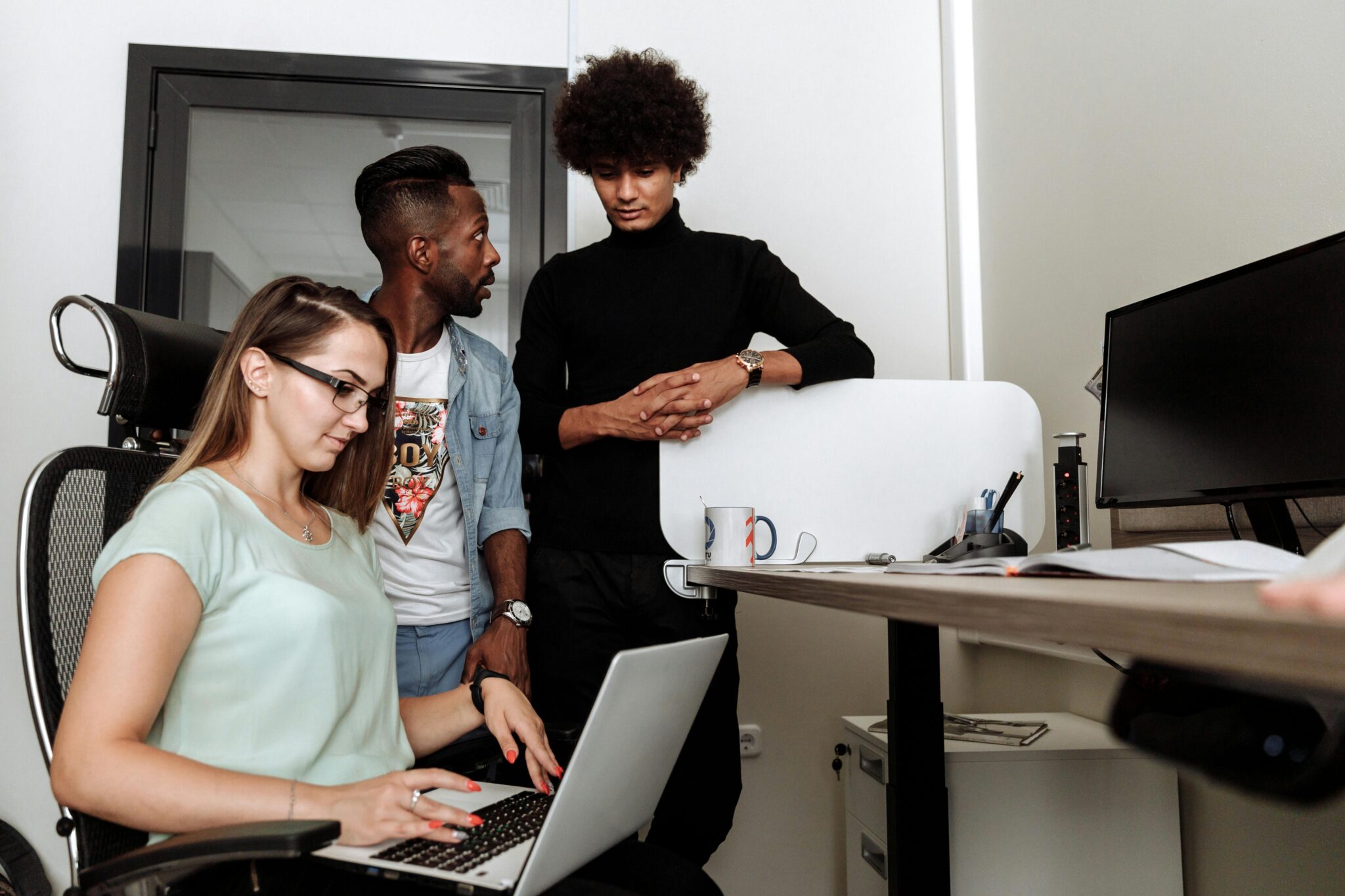 Three colleagues in an office setting, discussing work